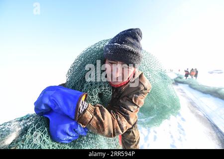 201227 -- FUHAI, 27 dicembre 2020 -- Un pescatore trasporta la rete durante la pesca invernale sul lago congelato Ulunggur nella contea di Fuhai, regione autonoma di Xinjiang Uygur della Cina nord-occidentale, 27 dicembre 2020. Ogni anno, i pescatori seguono il tradizionale metodo di pesca invernale mettendo sotto il ghiaccio una rete gigante per pescare sul lago Frozon Ulunggur, uno dei dieci laghi d'acqua dolce più grandi della Cina. CHINA-XINJIANG-FUHAI-ULUNGGUR LAGO-PESCA INVERNALE CN SADAT PUBLICATIONXNOTXINXCHN Foto Stock