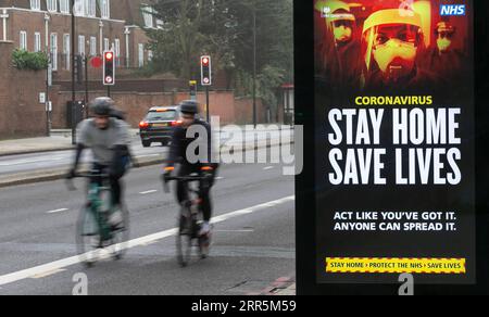 210110 -- LONDRA, 10 gennaio 2021 -- People Cycle Before an advertising board Reading Stay Home Save Lives in London, Britain, 10 gennaio 2020. I decessi correlati al coronavirus in Gran Bretagna hanno superato i 80.000 di sabato, mentre altri 1.035 sono stati segnalati nel paese. REGNO UNITO-LONDRA-COVID-19-CASI HanxYan PUBLICATIONxNOTxINxCHN Foto Stock