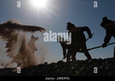 210113 -- AKSAY, 13 gennaio 2021 -- i lavoratori delle ferrovie puliscono la sabbia nella contea autonoma di Kazak di Aksay nel nord-ovest della Cina nella provincia del Gansu, 12 gennaio 2021. La ferrovia Dunhuang, che aprì completamente nel dicembre 2019, interseca le ferrovie esistenti, tra cui la ferrovia Lanzhou-Qinghai, la ferrovia Qinghai-Tibet e la ferrovia Lanzhou-Xinjiang, per formare la prima rete ferroviaria circolare nella regione nord-occidentale. Tra questi, la sezione da Yangguan a Shashangou si trova a Shazaoyuan, un luogo noto per il suo forte vento trasversale nella contea autonoma di Kazak di Aksay. La sabbia seppellirebbe la pista dal tempo t Foto Stock