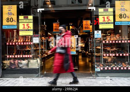 210123 -- BRUXELLES, 23 gennaio 2021 -- Una donna che indossa una maschera cammina davanti a un negozio con poster di vendita a Bruxelles, in Belgio, 22 gennaio 2021. Le vendite invernali annuali belghe sono iniziate il 4 gennaio. Per incrementare i consumi, le vendite invernali previste per quattro settimane sono state prorogate di due settimane fino al 15 febbraio. BELGIO-BRUXELLES-COVID-19-VENDITE INVERNALI ZhangxCheng PUBLICATIONxNOTxINxCHN Foto Stock