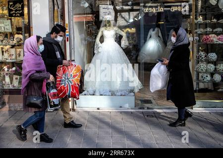 210128 -- TEHERAN, 28 gennaio 2021 -- la gente passa davanti a un negozio di abiti da sposa chiuso a Teheran, Iran, il 28 gennaio 2021. Per molti iraniani che cercano di legare il nodo, sono stati costretti ad apportare modifiche e adeguamenti ai loro piani di matrimonio, affrontando gli ostacoli causati dalla pandemia di COVID-19. Foto di /Xinhua IRAN-TEHERAN-COVID-19-WEDDING PLAN-CHANGE AhmadxHalabisaz PUBLICATIONxNOTxINxCHN Foto Stock