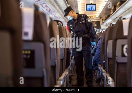 210202 -- URUMQI, 2 febbraio 2021 -- Zhang Jianzhi parla con i passeggeri durante i controlli di sicurezza sul treno D8806 nella regione autonoma di Xinjiang Uygur della Cina nordoccidentale, 30 gennaio 2021. Zhang Jianzhi, un poliziotto ferroviario di 27 anni che lavora a Urumqi, si occupa del suo terzo lavoro di punta per i viaggi del Festival di Primavera. Lavorando per più di 40 giorni consecutivi durante la corsa di viaggi del Festival di Primavera dello scorso anno, Zhang si è sentito dispiaciuto per non essere stato con la sua ragazza Zhao Lelin. Quest'anno, alla fine ha proposto alla sua ragazza sul suo familiare treno D8806. Ho programmato questa proposta speciale sul treno per sorprenderla. Foto Stock