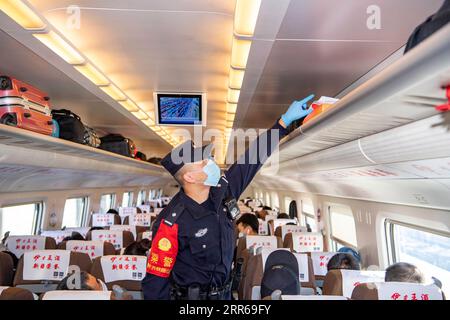 210202 -- URUMQI, 2 febbraio 2021 -- Zhang Jianzhi conduce controlli di sicurezza sul treno D8806 nella regione autonoma di Xinjiang Uygur della Cina nord-occidentale, 30 gennaio 2021. Zhang Jianzhi, un poliziotto ferroviario di 27 anni che lavora a Urumqi, si occupa del suo terzo lavoro di punta per i viaggi del Festival di Primavera. Lavorando per più di 40 giorni consecutivi durante la corsa di viaggi del Festival di Primavera dello scorso anno, Zhang si è sentito dispiaciuto per non essere stato con la sua ragazza Zhao Lelin. Quest'anno, alla fine ha proposto alla sua ragazza sul suo familiare treno D8806. Avevo programmato questa proposta speciale sul treno per sorprenderla, e anche nella speranza che lei lo facesse Foto Stock