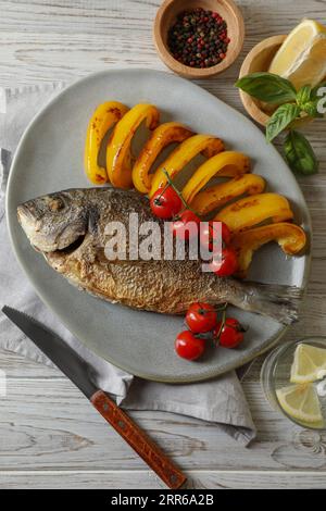 Delizioso pesce dorado arrosto servito con verdure su un tavolo di legno, piatto Foto Stock