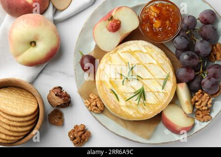 Gustoso formaggio brie al forno servito su un tavolo in marmo bianco, piatto Foto Stock