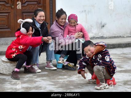 210203 -- LIANGSHAN, 3 febbraio 2021 -- Bamu Yubumu siede con i suoi figli di fronte alla sua residenza nel villaggio di Taoyuan, contea di Yuexi, prefettura autonoma di Liangshan Yi, provincia del Sichuan della Cina sud-occidentale, 22 gennaio 2021. Una giovane madre si è appoggiata arduamente in avanti per bilanciare il peso di un bagaglio grande sulla schiena e di un piccolo bambino nel braccio, mentre combatteva i suoi passi avanti. Questa era l'immagine che il reporter di Xinhua catturò vicino alla stazione ferroviaria di Nanchang, nella provincia di Jiangxi, nella Cina orientale, il 30 gennaio 2010. La foto intitolata Baby, Mom Takes You Home ha toccato i cuori di milioni di persone quando lo ha fatto Foto Stock