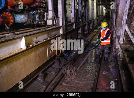 210209 -- ZHONGNING, 9 febbraio 2021 -- Un operaio pulisce i fanghi all'interno di un tunnel attraverso il fiume giallo nella contea di Zhongning, Zhongwei City, nella Cina nordoccidentale, nell'Autonomous Reigon di Ningxia Hui, 9 febbraio 2021. Più di 100 lavoratori sono ancora in servizio nel tunnel per garantire lo sviluppo del progetto in tempo nonostante il prossimo Festival di Primavera o il Capodanno lunare cinese. Questo tunnel, il secondo ad attraversare il fiume giallo a Ningxia, fa parte di un progetto più grande per fornire un servizio di riscaldamento ai residenti a Zhongning. CHINA-NINGXIA-TUNNEL ATTRAVERSO IL FIUME GIALLO CN FENGXKAIHUA PUBLICATIONXNOTXINXCHN Foto Stock