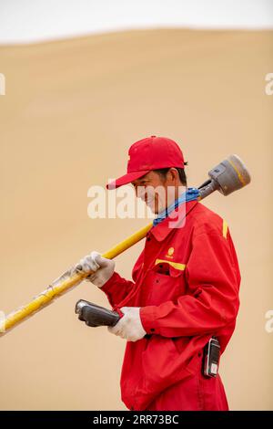 210310 --URUMQI, 10 marzo 2021 -- Feng Yongsheng del team geofisico di indagine lavora nel deserto di Taklimakan, regione autonoma di Xinjiang Uygur della Cina nordoccidentale, 25 febbraio 2021. Il deserto di Taklimakan, situato nel bacino del Tarim, nella regione autonoma di Xinjiang Uygur della Cina nord-occidentale, è una delle principali regioni petrolifere della Cina e una delle più difficili da esplorare a causa del suo ambiente duro e delle complicate condizioni sotterranee. Per esplorare le risorse di petrolio e gas sono necessari più processi, tra cui lo svolgimento di indagini geofisiche, in modo da raccogliere dati sismici per gettare solide basi Foto Stock