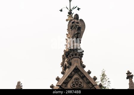 statua di angelo religioso in un tempio in un cimitero in una giornata nuvolosa all'aperto Foto Stock