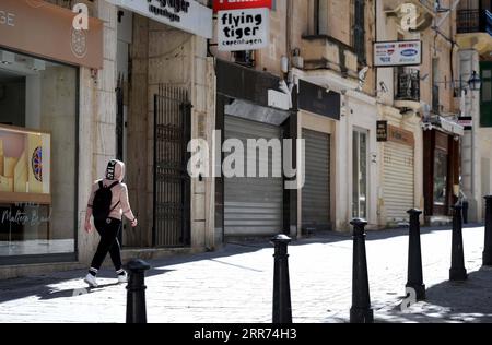 210311 -- LA VALLETTA, 11 marzo 2021 -- Una passeggiata pedonale passeggia accanto a negozi chiusi a la Valletta, Malta, 11 marzo 2021. Mercoledì il governo maltese ha annunciato la chiusura di scuole e negozi non essenziali in risposta a un picco nei nuovi casi di COVID-19, quasi due terzi dei quali sono attribuibili alla variante riportata per la prima volta nel Regno Unito. Le nuove misure, che saranno in vigore fino all'11 aprile, comprendono la chiusura di tutti i negozi non essenziali e di quelli che forniscono servizi non essenziali come parrucchieri ed estetiste, mentre la limitazione delle riunioni di gruppo in pubblico fino ad un massimo di quattro pipi Foto Stock