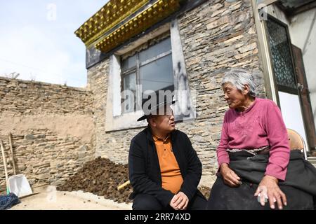 210312 -- YUSHU, 12 marzo 2021 -- Nyima L parla con una donna anziana nella Lab Township della contea di Chindu, prefettura autonoma tibetana di Yushu, provincia del Qinghai della Cina nord-occidentale, 9 marzo 2021. Nyima ha intenzione di aiutare la donna anziana a riparare la sua casa tradizionale. Nyima, 40 anni, nacque in una famiglia di pastori nella contea di Chindu nello Yushu. Suo padre è noto localmente come artigiano nella tradizionale architettura tibetana. Influenzato da suo padre, Nyima mostrò grande interesse per l'architettura tradizionale tibetana fin dalla sua infanzia. Nel 2010, un violento terremoto colpì Yushu e danneggiò molti tradi Foto Stock