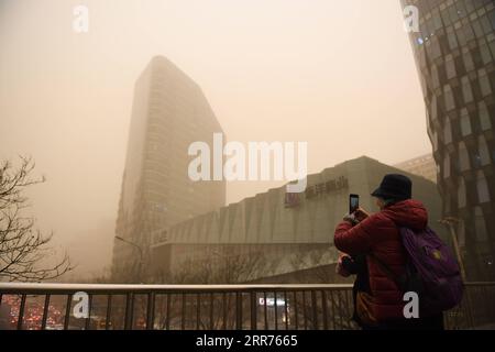 210315 -- PECHINO, 15 marzo 2021 -- Una donna scatta foto di edifici e strade avvolte dalla polvere su un ponte pedonale a Pechino, capitale della Cina, 15 marzo 2021. La polvere galleggiante ha colpito Pechino lunedì. CHINA-BEIJING-WEATHER-DUST CN JuxHuanzong PUBLICATIONxNOTxINxCHN Foto Stock