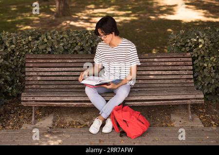 Adolescente asiatico con panchina da manuale Foto Stock