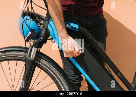 Ciclista che fissa la batteria della e-bike Foto Stock