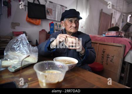 210326 -- HEFEI, 26 marzo 2021 -- Yan Mingyou cena nel suo dormitorio a Zhuwan Township della contea di Dingyuan, città di Chuzhou, provincia di Anhui della Cina orientale, 23 marzo 2021. Yan Mingyou, 92 anni, è ancora al posto di insegnare musica nelle scuole elementari rurali. Ritiratosi come insegnante rurale nel 1990, Yan si è offerto volontario per insegnare musica agli studenti delle scuole rurali. Nel 1953, Yan lasciò l'esercito e tornò nella sua città natale Zhuwan Township nella contea di Dingyuan. Ha rinunciato a un lavoro migliore presso il governo locale e ha scelto di lavorare nelle scuole rurali, insegnando varie materie come la politica, la musica e il CH Foto Stock