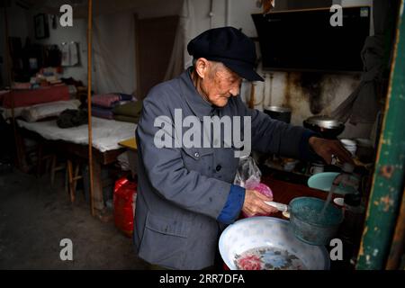 210326 -- HEFEI, 26 marzo 2021 -- Yan Mingyou prepara la cena nel suo dormitorio a Zhuwan Township della contea di Dingyuan, Chuzhou City, provincia di Anhui nella Cina orientale, 23 marzo 2021. Yan Mingyou, 92 anni, è ancora al posto di insegnare musica nelle scuole elementari rurali. Ritiratosi come insegnante rurale nel 1990, Yan si è offerto volontario per insegnare musica agli studenti delle scuole rurali. Nel 1953, Yan lasciò l'esercito e tornò nella sua città natale Zhuwan Township nella contea di Dingyuan. Rinunciò a un lavoro migliore presso il governo locale e scelse di lavorare nelle scuole rurali, insegnando varie materie come la politica, la musica e la musica Foto Stock