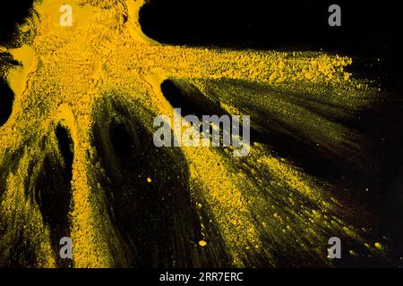 Colore polvere giallo che esplode sfondo nero Foto Stock