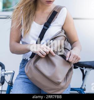 Primo piano della giovane donna che chiude la zip dello zaino Foto Stock