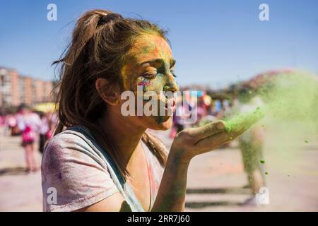 Primo piano della giovane donna che soffia il colore di holi Foto Stock
