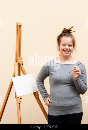 Smiley ragazza con sindrome di Down in posa con la spazzola Foto Stock