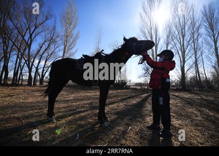 210403 -- BURQIN, 3 aprile 2021 -- Yernar Tiemerbek, uno studente senventh della Oymak Boarding School, tocca un cavallo durante una classe equestre nella contea di Burqin, nella regione autonoma dello Xinjiang Uygur della Cina nord-occidentale, 30 marzo 2021. Le persone nella regione autonoma di Xinjiang Uygur hanno una tradizione di allevamento e equitazione. La Oymak Boarding School ha iniziato a offrire lezioni di equitazione alla fine del 2019. Gli studenti, la maggior parte dei quali provengono da famiglie di pastori, imparano sia la conoscenza teorica che la pratica dell'equitazione nelle classi equestri. Dopo le lezioni, gli studenti diventano più forti fisicamente e amano la vita Foto Stock
