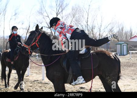210403 -- BURQIN, 3 aprile 2021 -- Parasat Zhumabek front, uno studente senventh della Oymak Boarding School, sale su un cavallo durante una lezione di equitazione nella contea di Burqin, nella regione autonoma di Xinjiang Uygur della Cina nord-occidentale, 30 marzo 2021. Le persone nella regione autonoma di Xinjiang Uygur hanno una tradizione di allevamento e equitazione. La Oymak Boarding School ha iniziato a offrire lezioni di equitazione alla fine del 2019. Gli studenti, la maggior parte dei quali provengono da famiglie di pastori, imparano sia la conoscenza teorica che la pratica dell'equitazione nelle classi equestri. Dopo le lezioni, gli studenti diventano più forti fisicamente e amano Foto Stock