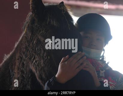 210403 -- BURQIN, 3 aprile 2021 -- Parasat Zhumabek, uno studente senventh della Oymak Boarding School, tocca un cavallo durante una classe equestre nella contea di Burqin, nella regione autonoma dello Xinjiang Uygur della Cina nord-occidentale, 29 marzo 2021. Le persone nella regione autonoma di Xinjiang Uygur hanno una tradizione di allevamento e equitazione. La Oymak Boarding School ha iniziato a offrire lezioni di equitazione alla fine del 2019. Gli studenti, la maggior parte dei quali provengono da famiglie di pastori, imparano sia la conoscenza teorica che la pratica dell'equitazione nelle classi equestri. Dopo le lezioni, gli studenti diventano più forti fisicamente e amano la vita Foto Stock