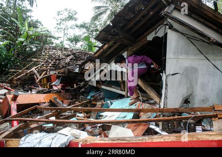 210411 -- GIAVA ORIENTALE, 11 aprile 2021 -- Un ragazzo esce da una casa danneggiata dopo un terremoto di magnitudo 6,1 ha colpito il villaggio di Kali Uling a Lumajang, Giava Orientale, Indonesia, 11 aprile 2021. Sei persone sono state uccise, un'altra è stata gravemente ferita e decine di edifici sono stati danneggiati dopo che un terremoto di magnitudo 6,1 ha scosso la provincia occidentale indonesiana di Giava orientale sabato, hanno detto i funzionari. Il terremoto ha colpito alle 14:00, ora di Giacarta 0700 GMT, con l'epicentro 96 km a sud della città di Kepanjen, nel distretto di Malang, con una profondità di 80 km, Andry Sembiring, funzionario dell'Agenzia di Meteorologia, Climatologia e Geofisica, S Foto Stock