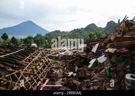 210411 -- GIAVA ORIENTALE, 11 aprile 2021 -- Un uomo cammina vicino a case danneggiate dopo che un terremoto di magnitudo 6,1 ha colpito il villaggio di Kali Uling a Lumajang, Giava Orientale, Indonesia, 11 aprile 2021. Sei persone sono state uccise, un'altra è stata gravemente ferita e decine di edifici sono stati danneggiati dopo che un terremoto di magnitudo 6,1 ha scosso la provincia occidentale indonesiana di Giava orientale sabato, hanno detto i funzionari. Il terremoto colpì alle 14:00, ora di Giacarta, 0700 GMT, con l'epicentro a 96 km a sud della città di Kepanjen, nel distretto di Malang, con una profondità di 80 km, Andry Sembiring, un funzionario della Meteorologia, Climatologia e Geofisica Agenc Foto Stock