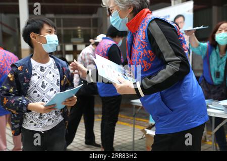 210415 -- HONG KONG, 15 aprile 2021 -- Un volontario distribuisce opuscoli sulla sicurezza nazionale a un bambino nel sud della Cina a Hong Kong, il 15 aprile 2021. Giovedì Hong Kong ha abbracciato la sua prima giornata nazionale per l'educazione alla sicurezza dopo che la legge sulla salvaguardia della sicurezza nazionale nella regione amministrativa speciale di Hong Kong HKSAR è entrata in vigore a metà del 2020. Varie attività, tra cui conferenze, mostre, muri a mosaico e porte aperte di servizi disciplinati, sono state svolte per sensibilizzare l'opinione pubblica sulla salvaguardia della sicurezza nazionale nel polo finanziario globale. CINA-HONG KONG-SICUREZZA NAZIONALE Foto Stock