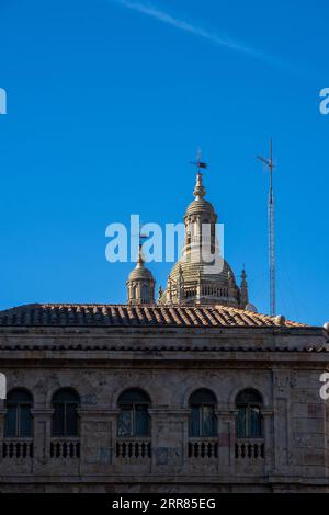 Cupole romaniche dell'antica cattedrale di Salamanca dietro la facciata e il tetto di un edificio classico e monumentale. Castilla y León, Spagna. Foto Stock