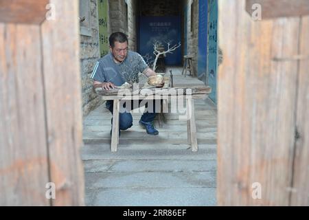 210421 -- JINJIANG, 21 aprile 2021 -- Cai Jingxiang realizza opere d'arte con i detriti delle barche, conchiglie e corallum rotto nella sua sala espositiva di gallerie marine nella città di Jinjiang, nella provincia del Fujian della Cina sud-orientale, il 19 aprile 2021. CAI Jingjiang, un designer di pubblicità di carriera, è tornato cinque anni fa nella sua città natale al Tangdong Village, Jinjing Township della città di Jinjiang. Ha trovato ispirazione dalle deriva marine che si sono gettate a riva vicino al suo villaggio, molte delle quali in forme uniche. Un giorno dopo l'altro, Cai cercò attraverso la spiaggia e portò a casa drift con potenziale artistico, e tu Foto Stock