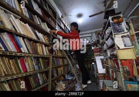 210422 -- HEFEI, 22 aprile 2021 -- Chen Guixia riordina le librerie della Zengzhi Bookshop di Hefei, provincia di Anhui, Cina orientale, 19 aprile 2021. Sin dalla sua apertura, 21 anni fa, la Zengzhi Bookshop, un rivenditore di libri di seconda mano non descritto nel centro di Hefei, è stata salutata come un punto di riferimento intellettuale tra gli appassionati di libri locali. Il suo defunto proprietario, Zhu Chuanguo, vantava una collezione di 000 libri usati, tutti acquistati da lettori ordinari e centri di riciclaggio. Secondo la visione di Zhu, i libri di scarto possono rivelarsi illuminanti per qualcun altro che merita quindi un lettore-fritta Foto Stock