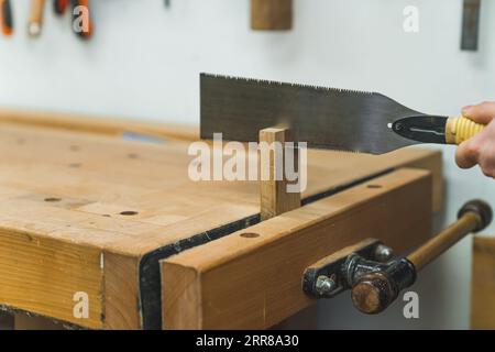 Utilizzo di morsa da banco per il taglio del legno con una sega a mano . Foto di alta qualità Foto Stock