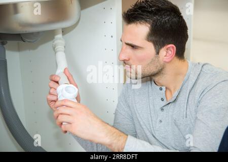 uomo che fissa sotto il lavandino in cucina Foto Stock