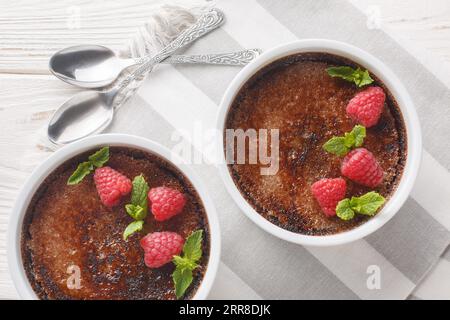 Dessert tradizionale alla crema di cioccolato brulee con zucchero di canna caramellato da vicino in una camicia sul tavolo. Vista superiore orizzontale dall'alto Foto Stock