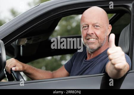 autista uomo felice maturo che dà un doppio pollice in alto Foto Stock