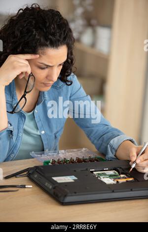 giovane donna che fissa i componenti del pc in classe Foto Stock