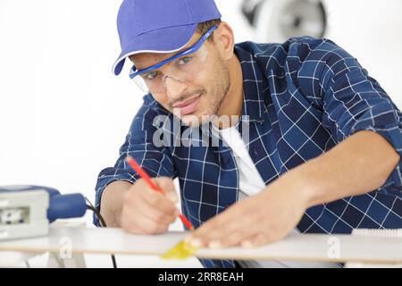 falegname con disegno a matita su un pezzo di legno Foto Stock