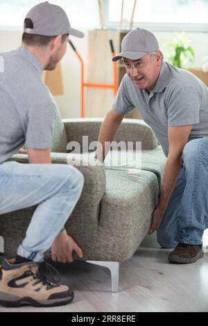 due uomini che trasportano divano Foto Stock