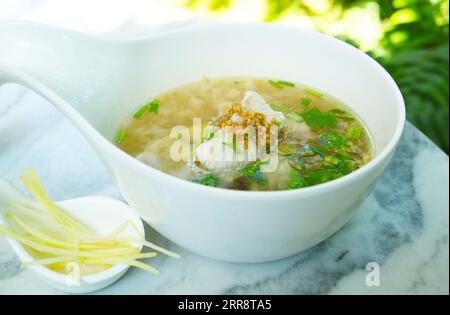 Delizioso porridge di riso in stile cinese con pesce servito sul tavolo Foto Stock