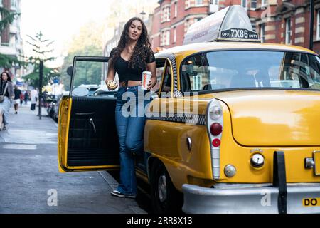 L'EDITORIALE UTILIZZA SOLO i gradini francesi di Imogen fuori dal taxi giallo di DUNKIN' UK, che dispone di uno stand fotografico all'interno, per annunciare la rapida espansione della società nella capitale britannica. Data foto: Giovedì 7 settembre 2023. Foto Stock