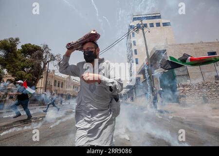 News Bilder des Tages 210521 -- BETLEMME, 21 maggio 2021 -- Un manifestante corre per coprire le bombole di gas lacrimogeni sparate dai soldati israeliani durante una protesta a sostegno dei palestinesi a Gerusalemme e nella Striscia di Gaza, nella città di Betlemme in Cisgiordania, il 21 maggio 2021. Foto di /Xinhua MIDEAST-BETHLEHEM-CLASHES LuayxSababa PUBLICATIONxNOTxINxCHN Foto Stock