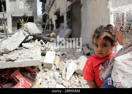 210521 -- GAZA, 21 maggio 2021 -- Una donna palestinese tiene il suo bambino mentre ispeziona la sua casa distrutta a seguito di un attacco aereo israeliano, dopo il cessate il fuoco tra Israele e Hamas, nella città settentrionale di Beit Hanoun, nella Striscia di Gaza, il 21 maggio 2021. Un accordo di cessate il fuoco di mediazione egiziana è entrato in vigore già venerdì tra Israele e Hamas, che governa la Striscia di Gaza, ponendo fine allo spargimento di sangue di 11 giorni. I combattimenti tra Israele e i gruppi militanti guidati da Hamas nella Striscia di Gaza hanno causato più di 100 morti e decine di migliaia di sfollati. Foto di /Xinhua MIDEAST-GAZA-CESSATE IL FUOCO R Foto Stock