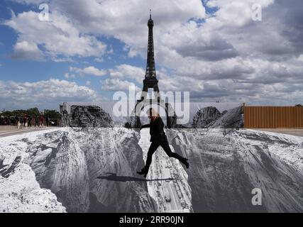 210521 -- PARIGI, 21 maggio 2021 -- Una donna posa per le foto in piazza Trocadero vicino alla Torre Eiffel, dove l'artista e fotografo francese conosciuto come JR ha allestito le sue opere, a Parigi, in Francia, il 21 maggio 2021. FRANCIA-PARIGI-TORRE EIFFEL-STREET ART GAOXJING PUBLICATIONXNOTXINXCHN Foto Stock