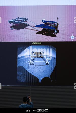 210522 -- PECHINO, 22 maggio 2021 -- Un membro dello staff registra il processo del primo rover Marte cinese, Zhurong, che scende dalla sua piattaforma di atterraggio alla superficie marziana dallo schermo del Beijing Aerospace Control Center di Pechino, capitale della Cina, 22 maggio 2021. Il primo rover marziano della Cina, Zhurong, è sceso dalla piattaforma di atterraggio alla superficie marziana sabato, lasciando le prime impronte del paese sul pianeta rosso. La prima unità di successo di Zhurong ha reso la Cina il secondo paese dopo gli Stati Uniti ad atterrare e gestire un rover su Marte. EYESONSCI CHINA-BEIJING-MARS ROVER-DRIVE C. Foto Stock