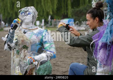 210606 -- VANCOUVER, 6 giugno 2021 -- Una donna scatta foto di una figura fatta con plastiche rimosse dalle coste a Kitsilano Beach a Vancouver, British Columbia, Canada, il 6 giugno 2021. Creato dall'artista multidisciplinare Caitlin Doherty e realizzato con materie plastiche rimosse dalle coste canadesi, un insieme di figure chiamate "beachgoers" di plastica incarnano il contributo collettivo delle persone all'inquinamento plastico, portando in primo piano il tema dell'inquinamento costiero. Foto di /Xinhua CANADA-VANCOUVER-INSTALLATIONS-PLASTIC BEACHGOERS LiangxSen PUBLICATIONxNOTxINxCHN Foto Stock