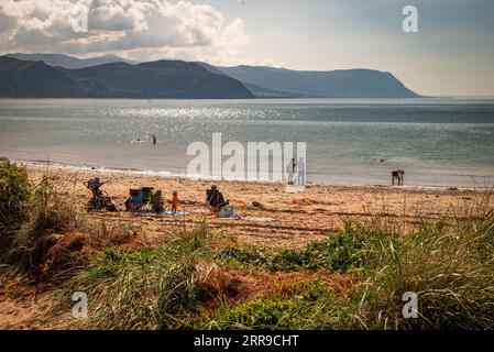 Le famiglie al sole sulla costa occidentale di Llandudno, nel Galles del Nord, guardando la baia di Conwy. Foto Stock
