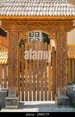 Le porte frontali in legno finemente scolpite continuano a essere una caratteristica di molte case di villaggio nella regione di Maramureș (Poienile Izei, Maramureș, Romania) Foto Stock