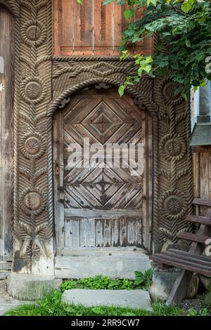 Le porte anteriori in legno, finemente intagliate, continuano a essere una caratteristica di molte case di villaggio nella regione di Maramureș (Breb, Maramureș, Romania) Foto Stock